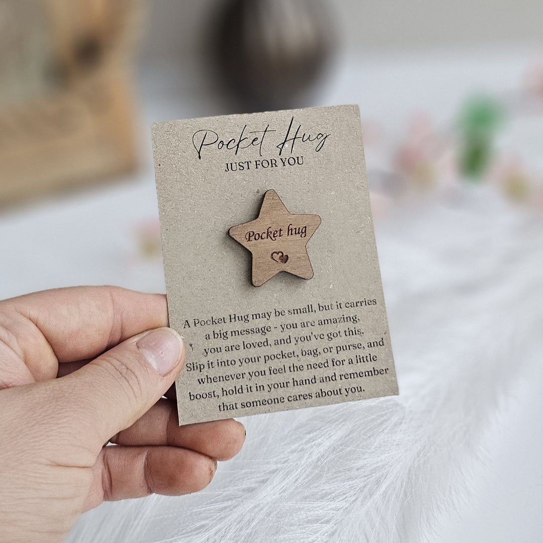A hand holding a small wooden star-shaped object with text on it.