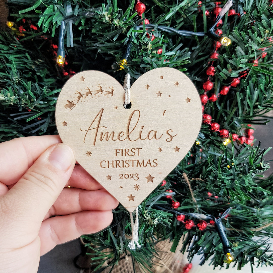 a person holding a wooden heart ornament in front of a christmas tree