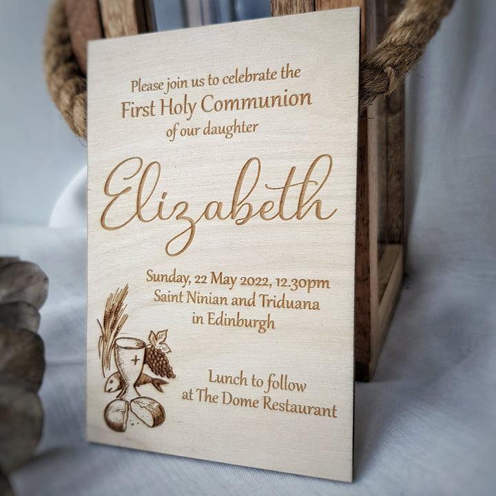 A wooden sign with text inviting people to a First Holy Communion celebration for Elizabeth, featuring an image of bread and wine.