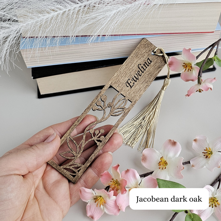 a person is holding a bookmark with flowers and a feather