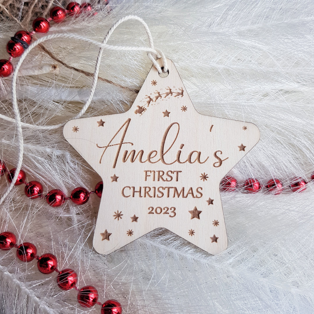 a wooden star ornament with a first christmas message