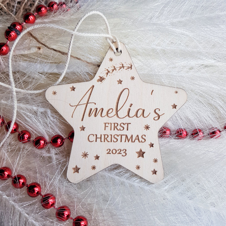 a wooden star ornament with a first christmas message