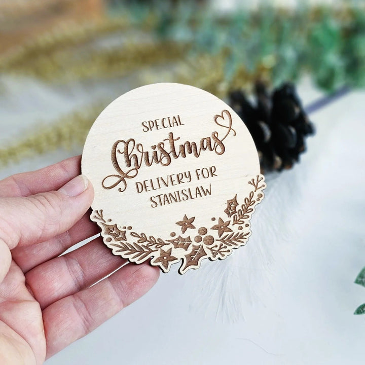 A hand holding a wooden coaster with the text "Special Christmas Delivery for Stanislaw" engraved on it.