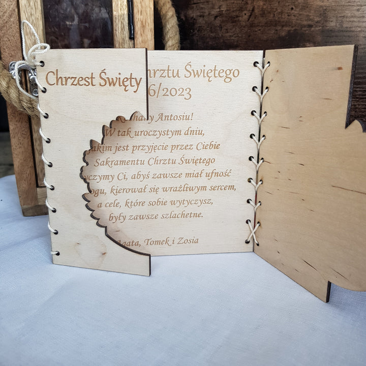 a wooden wedding invitation with a lace-like texture, displaying the text "Chrzest Swiey 6/2023" and a message about the wedding ceremony.