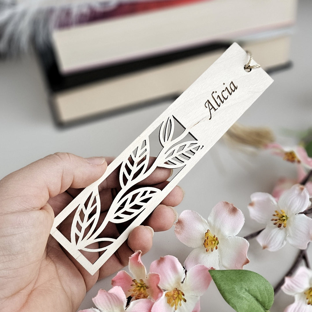 a person holding a wooden name tag with flowers in the background