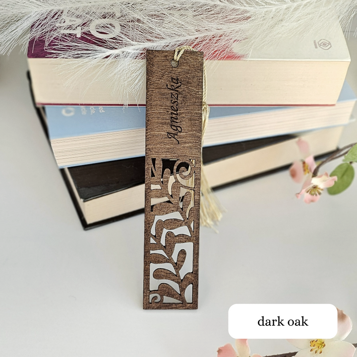 a bookmark with a name on it next to a stack of books