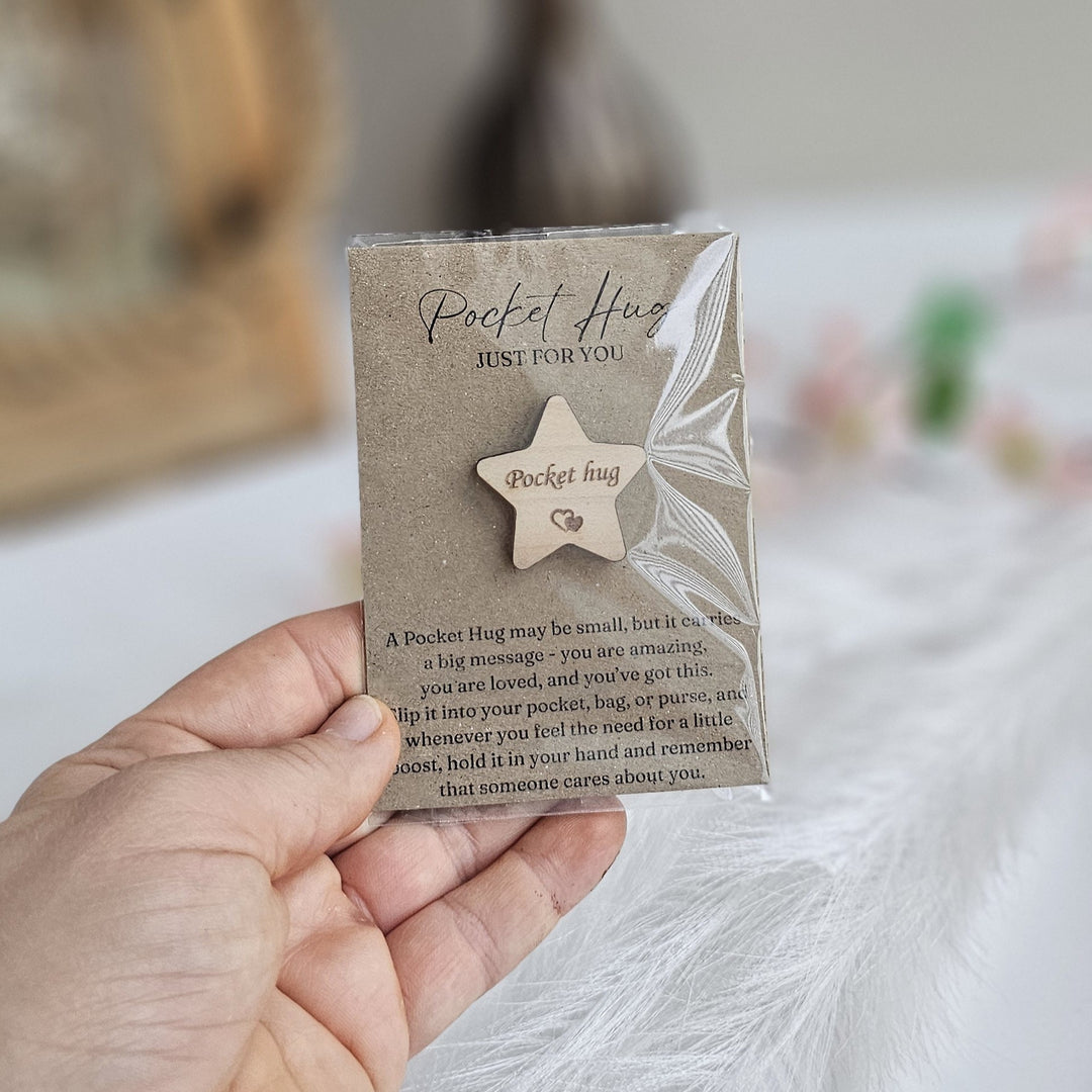 A person's hand holding a small wooden star-shaped object with text on it.