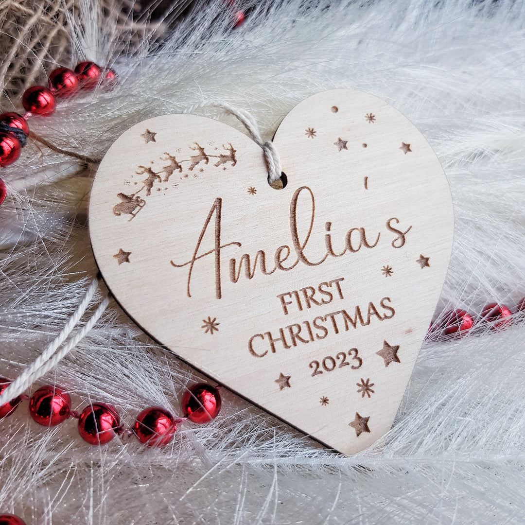 a wooden heart shaped ornament with a first christmas message