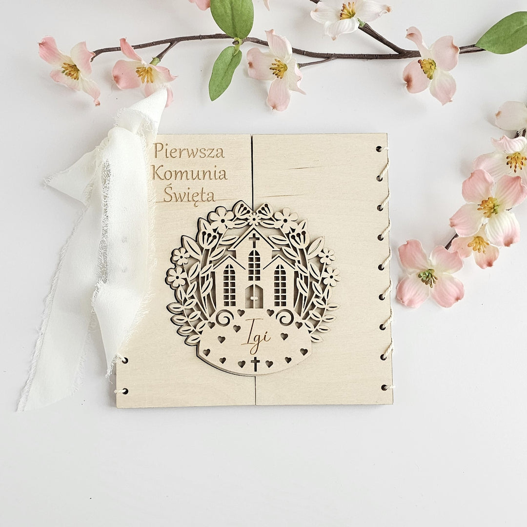 a wooden greeting card with a wreath design and a small house, placed on a white background.