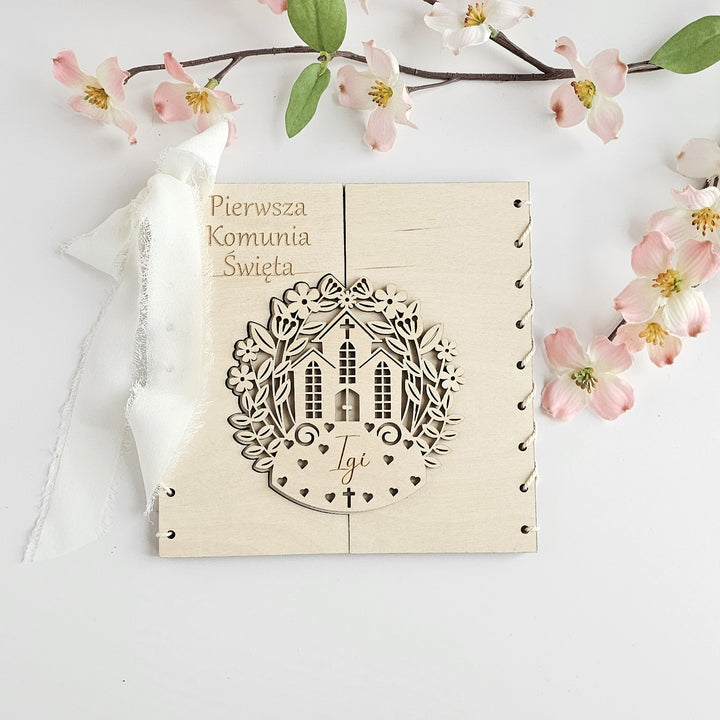 a wooden greeting card with a wreath design and a small house, placed on a white background.