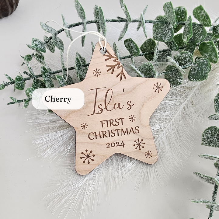 a wooden star ornament with a first christmas message