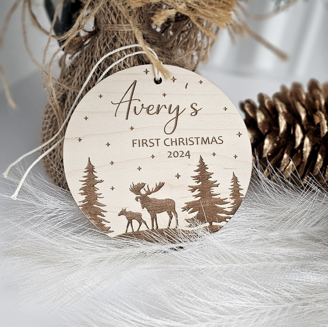 A wooden ornament with a deer silhouette and starry night sky design, along with the text "Avery's FIRST CHRISTMAS 2023".