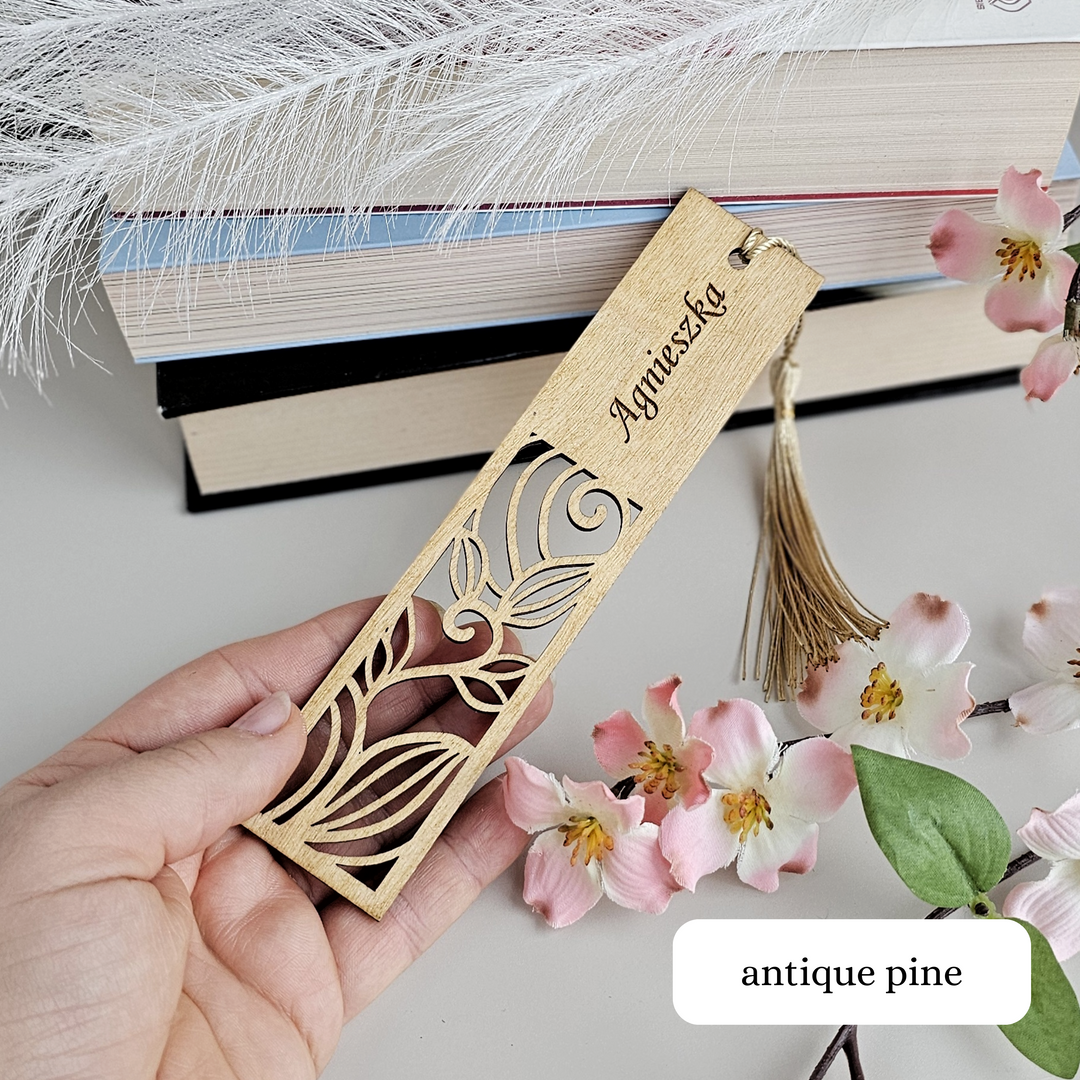 a person holding a wooden bookmark next to flowers