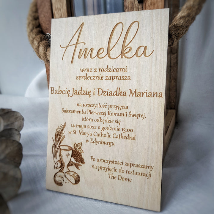a wooden sign with text and an illustration of a chalice and bread, placed on a table.