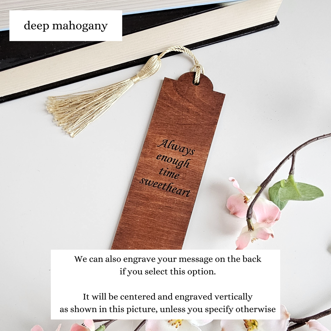 A wooden bookmark with a tassel and a small flower branch on a white surface.