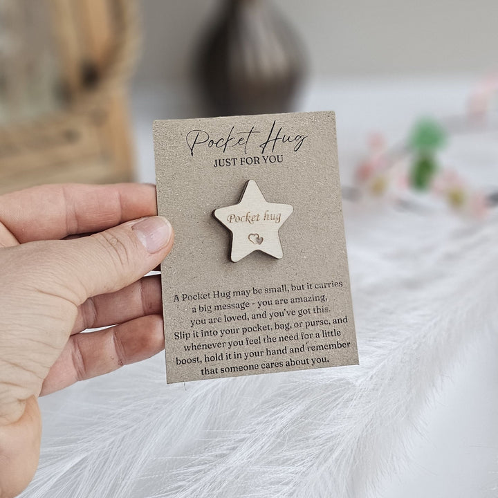 A hand holding a small wooden star-shaped object with text on it.
