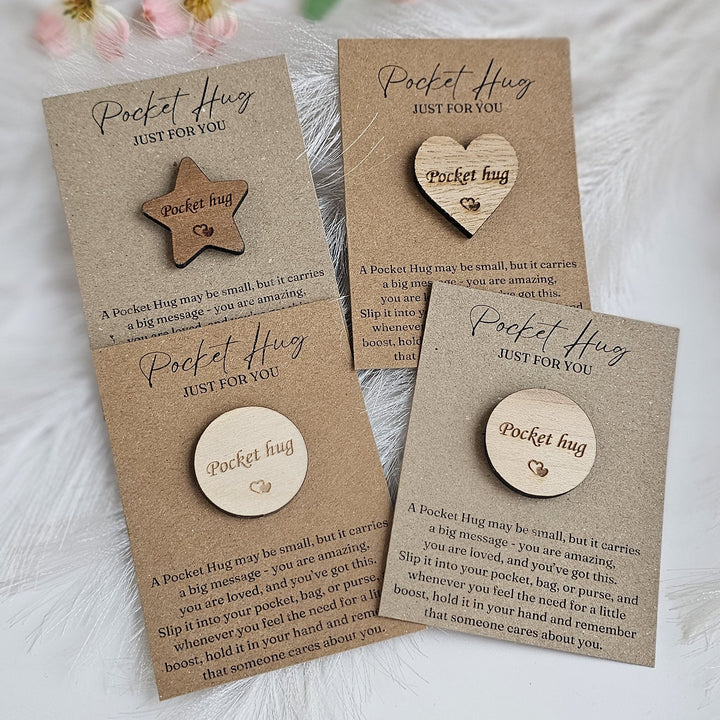 three wooden heart-shaped or star-shaped magnets with the text "Pocket Hug" written on them, along with a description of what they are.