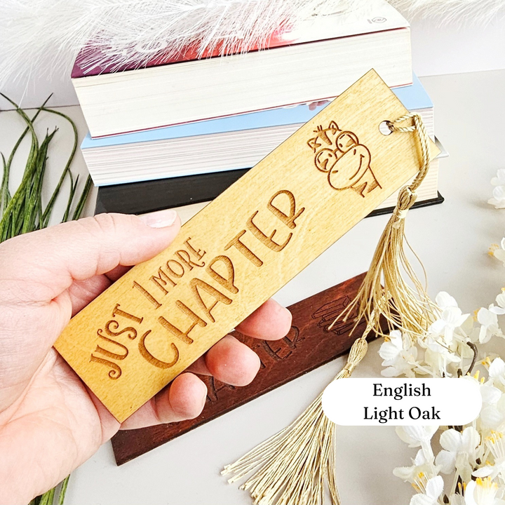 a person holding a wooden bookmark that says, just more sharp english light oak