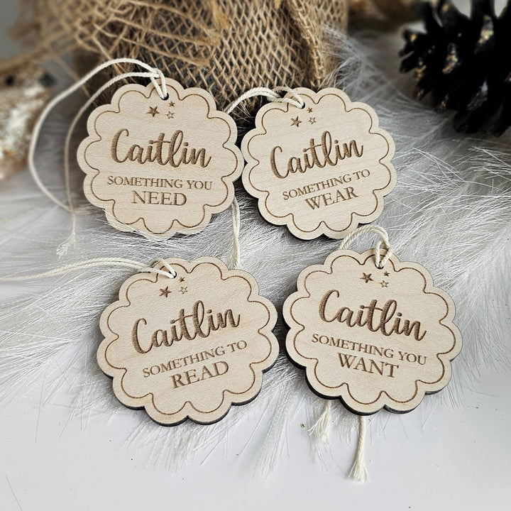four wooden tags with the name "Caitlin" printed on them, along with phrases such as "Something you need", "Something you wear", "Something you read", and "Something you want".