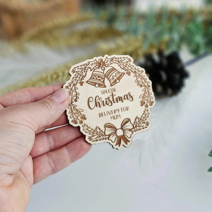 A hand holding a wooden Christmas card with the text "Special Christmas" and "Deliver for Mom" printed on it.