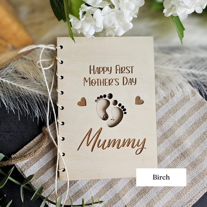 A wooden card with a mother and child's footprint design, along with the text "Happy First Mother's Day Mummy" and the word "Birches" written on it.