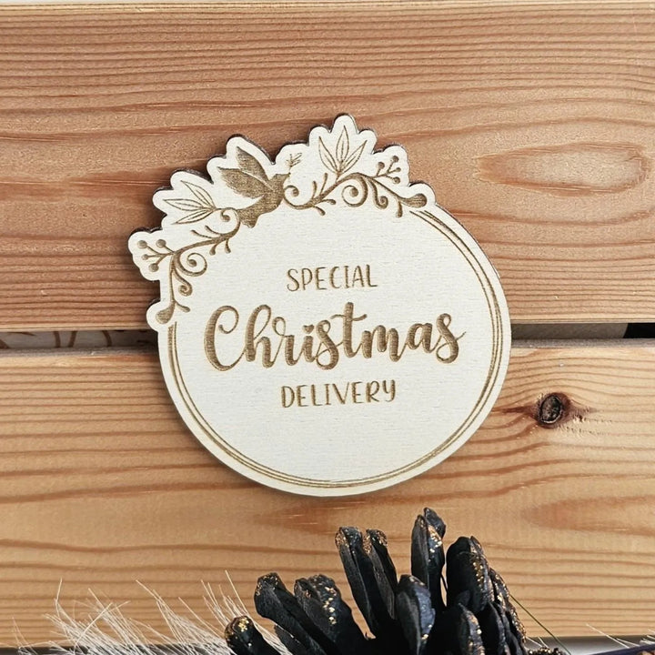 A wooden sign with the text "SPECIAL CHRISTMAS DELIVERY" engraved on it, placed on a wooden surface.