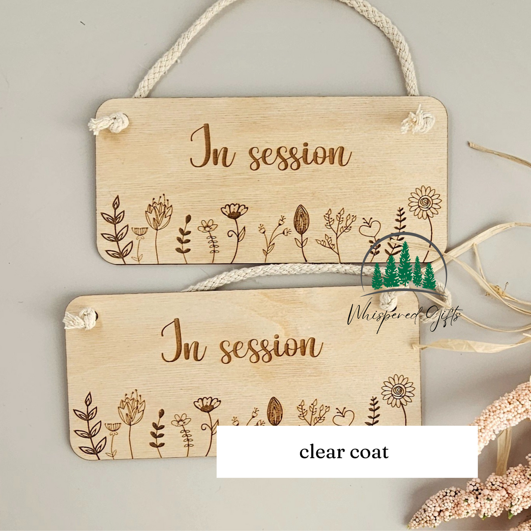 two wooden signs with the text "In session" engraved on them, hanging on a rope.