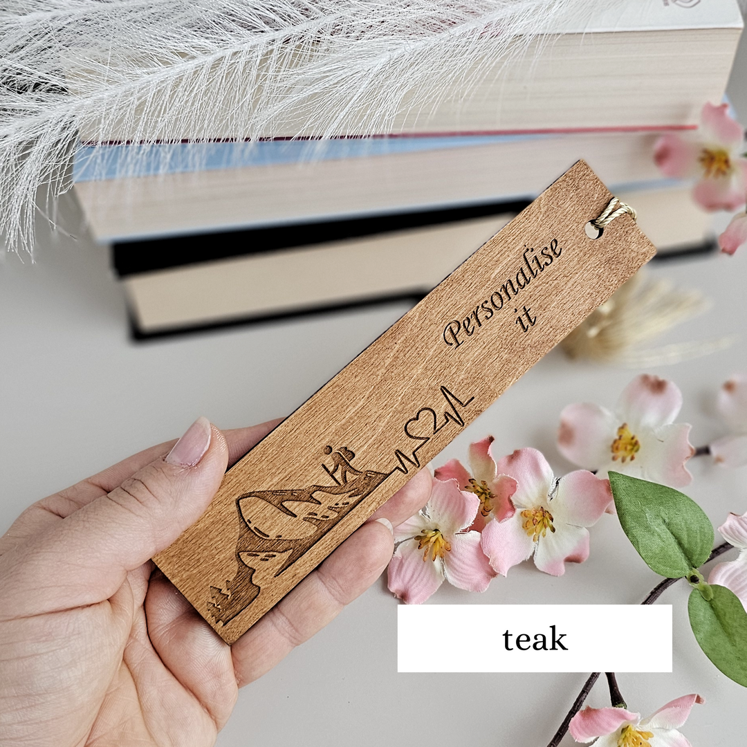 a person holding a wooden bookmark with the words teak on it