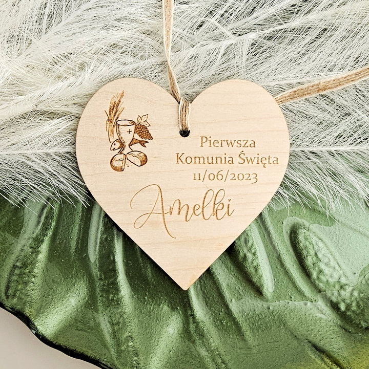 A wooden heart-shaped tag with text and an engraved image, placed on a green leaf-like surface.