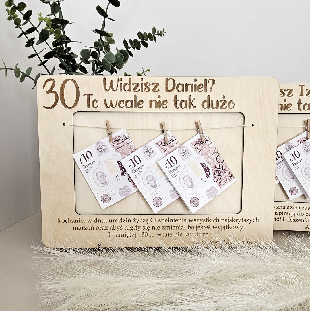 A wooden frame with a plant in the background and several pieces of money hanging from it.