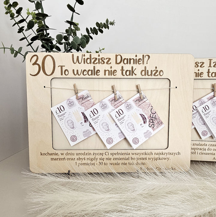 A wooden frame with a plant in the background and several pieces of money hanging from it.