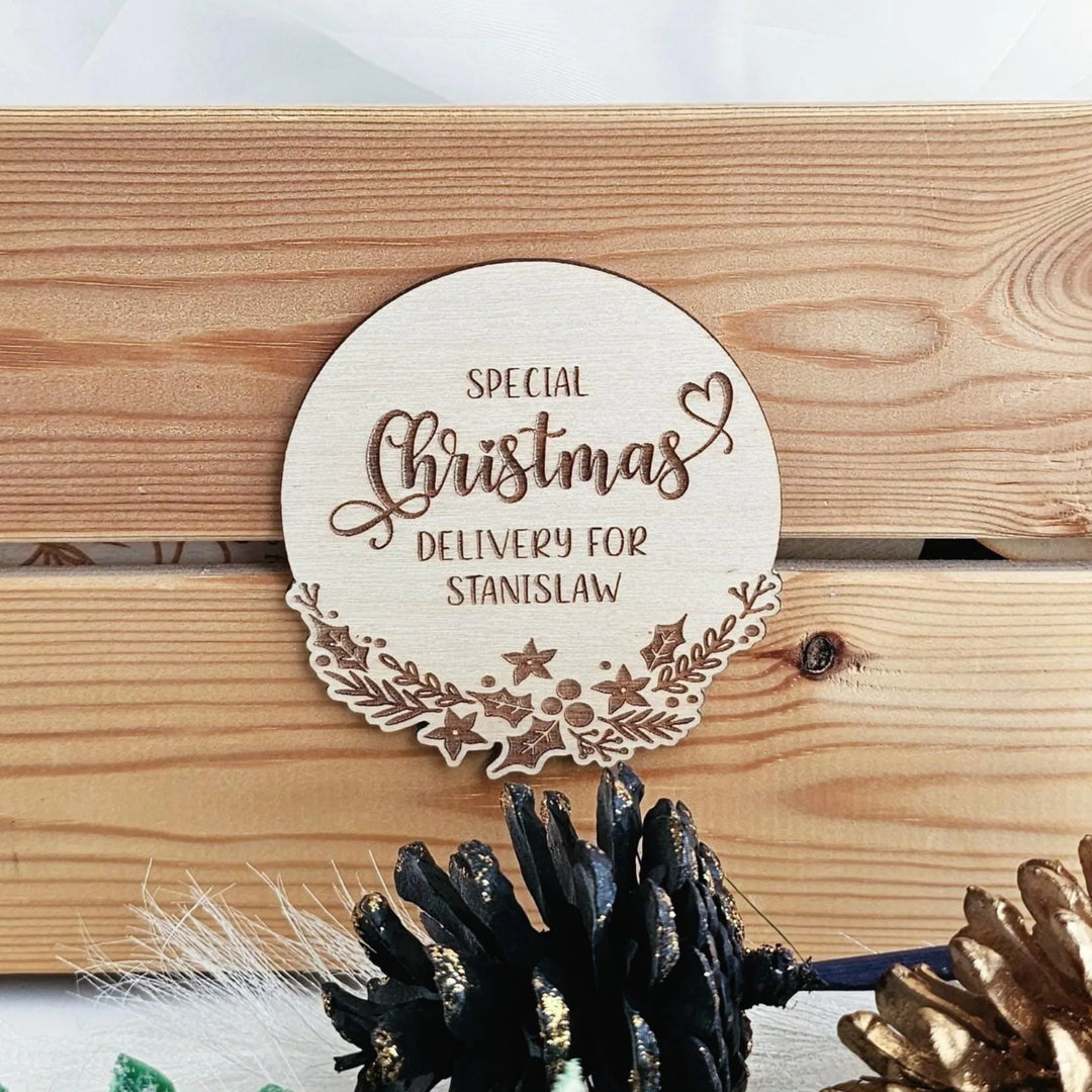 a wooden sign with the text "SPECIAL CHRISTMAS DELIVERY FOR STANISLAW" on it, placed on a wooden surface.