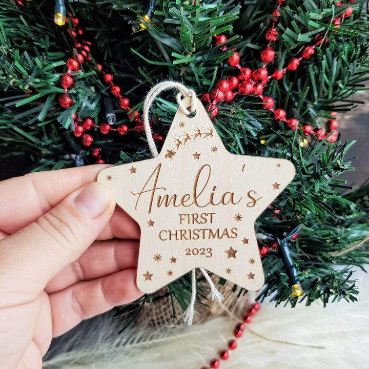 a person holding a wooden star ornament in front of a christmas tree