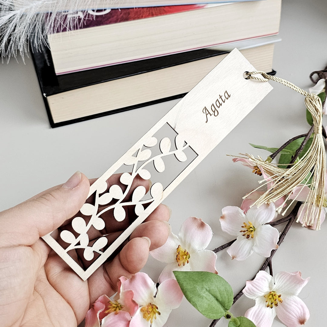 a person holding a bookmark with a flower on it