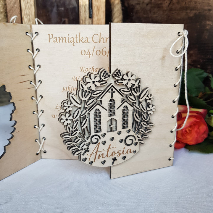 A wooden wedding invitation featuring a floral design and the name 'Antosia'.