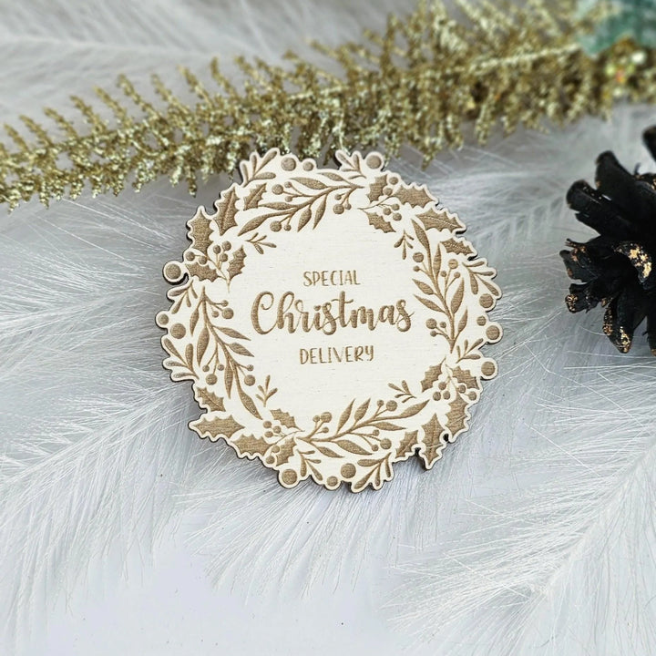 A wooden Christmas card with the text "SPECIAL CHRISTMAS DELIVERY" is displayed on a white background, surrounded by decorative feathers and pine cones.