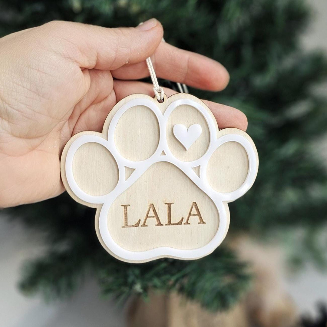 Personalised plywood and acrylic pet paw ornament with engraved name hanging on a Christmas tree.