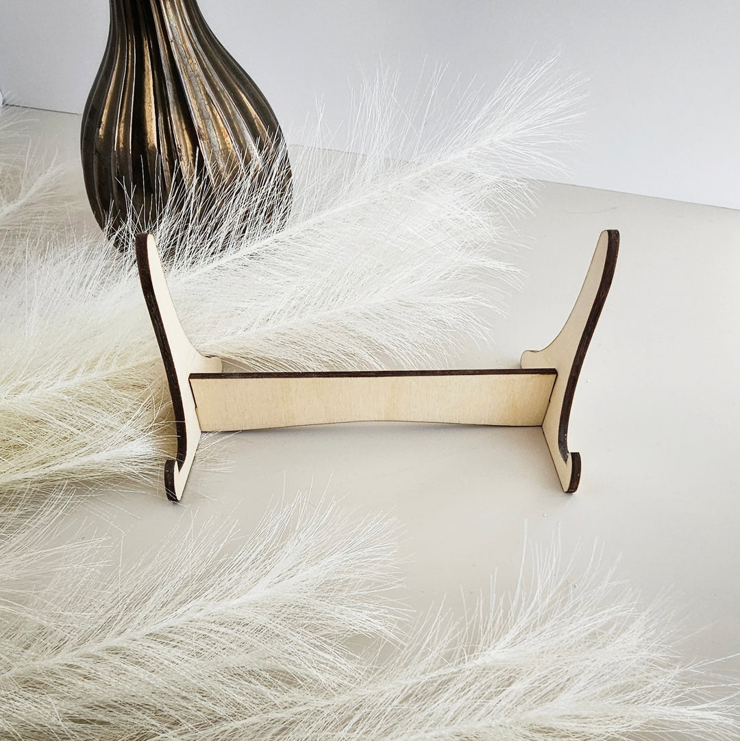 a wooden stand with a decorative element, possibly a vase or a feather, placed on a white surface.