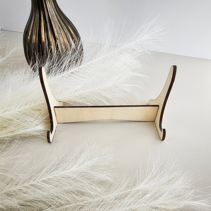 a wooden stand with a decorative element, possibly a vase or a feather, placed on a white surface.