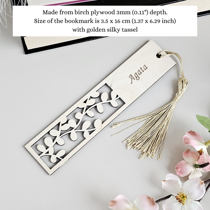 a bookmark with a tassel and flowers on a table