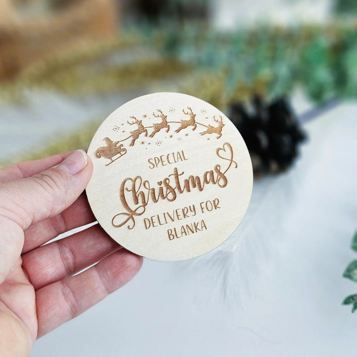 A hand holding a wooden coaster with the text "SPECIAL CHRISTMAS DELIVERY FOR BLANKA" engraved on it.