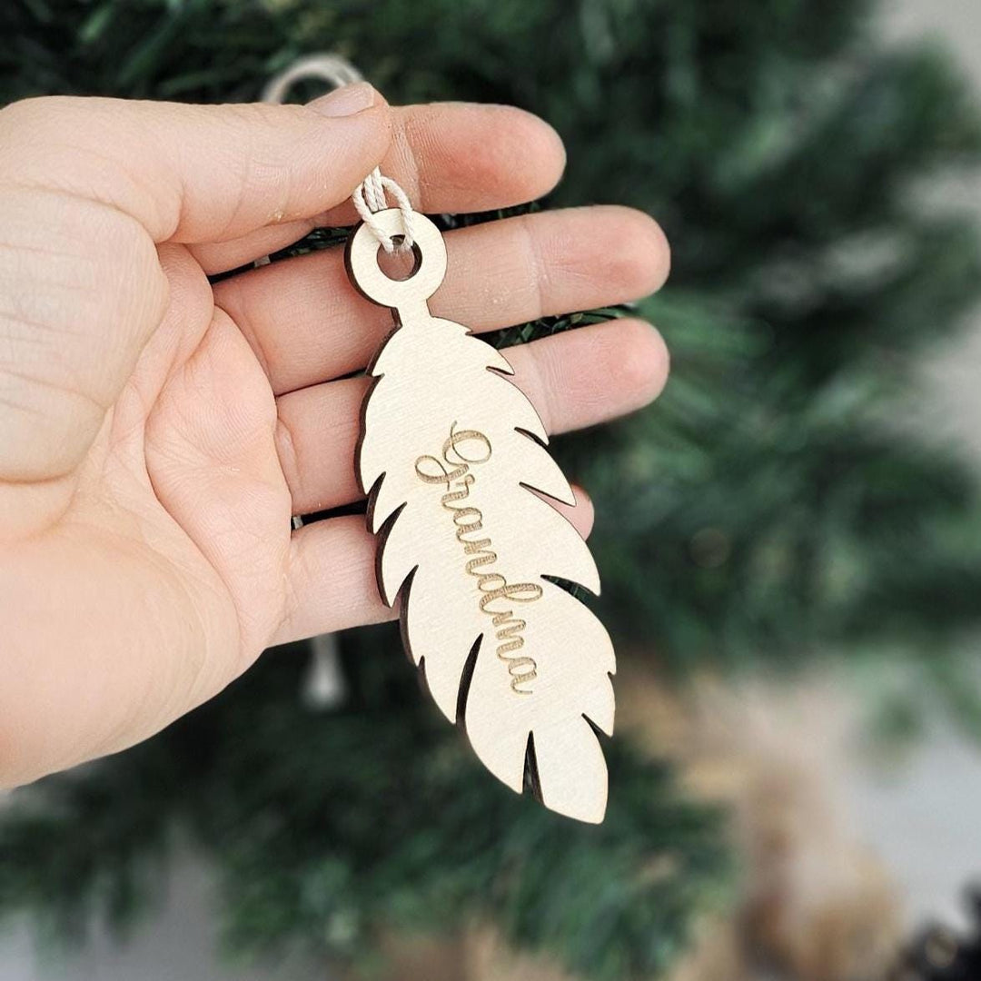 Wooden feather keepsake with engraved text displayed beside Christmas tree.