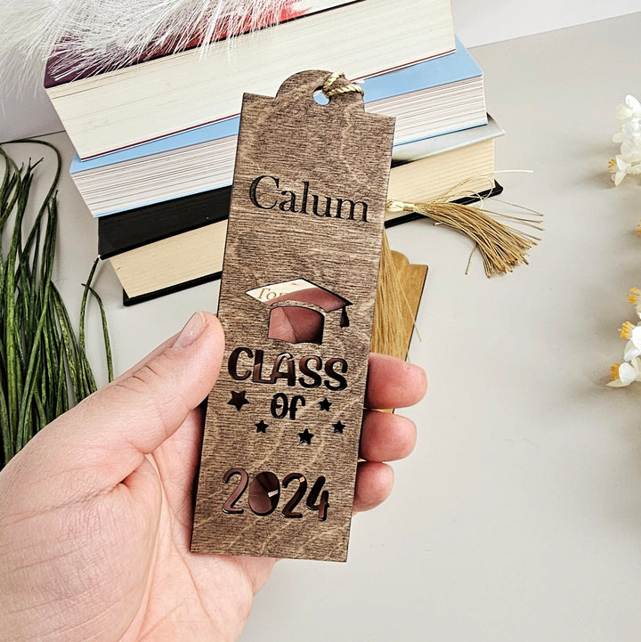 a person holding a wooden bookmark with the words class of 202 printed on it