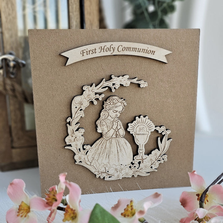 a wooden card with a floral design and a figure of a young girl, likely representing a first Holy Communion scene.