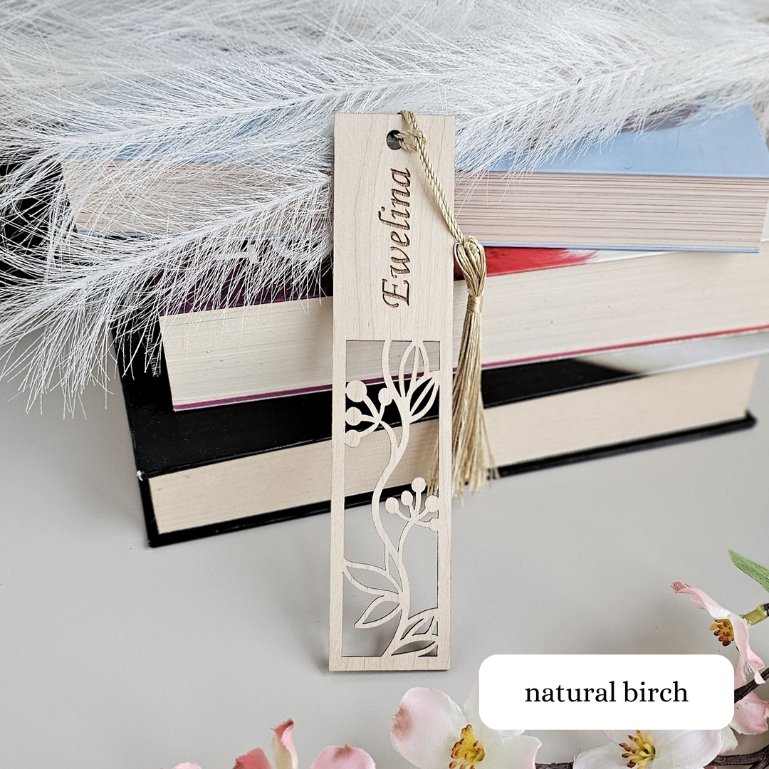 a bookmark with a flower on it next to a pile of books