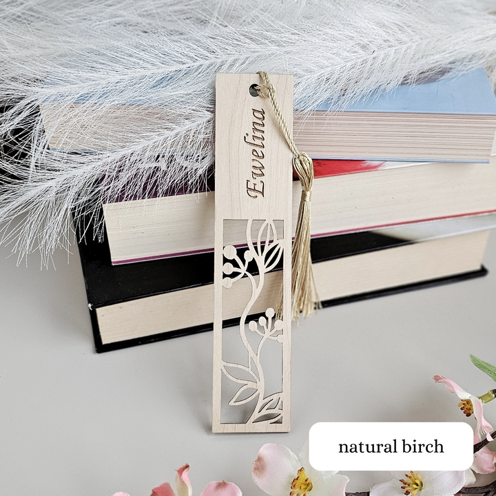 a bookmark with a flower on it next to a pile of books