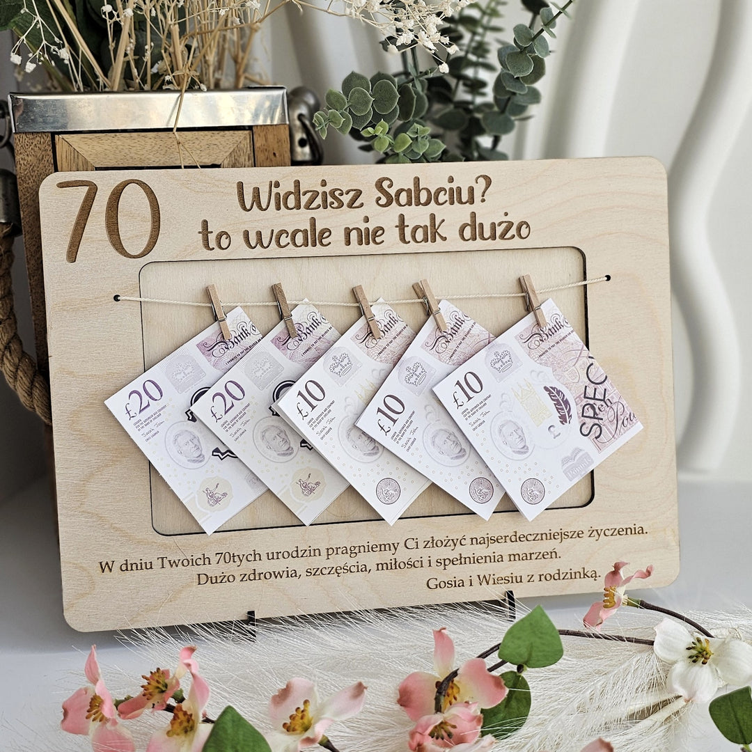 A wooden frame with money notes attached to it, displaying the text "Widzisz Sabciu? to wale nie tak duzo" and "70" written on it.