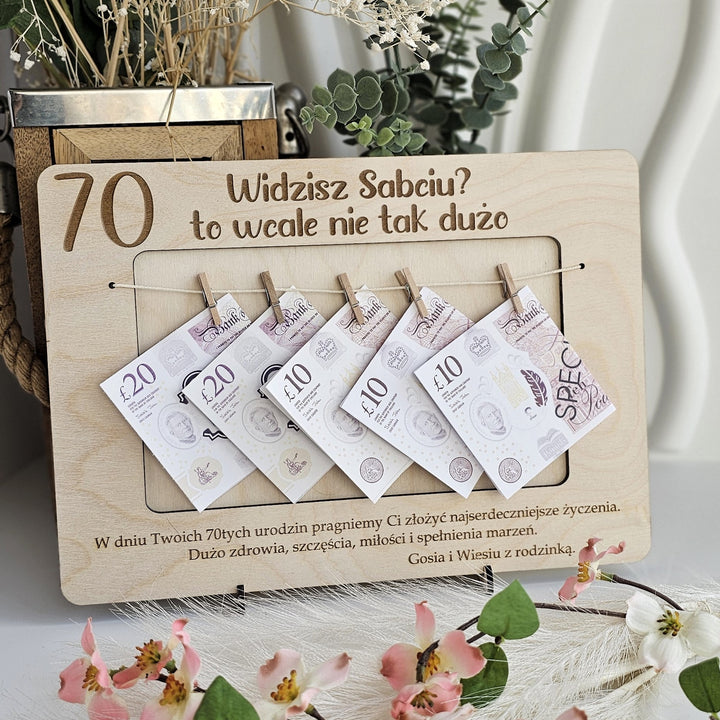 A wooden frame with money notes attached to it, displaying the text "Widzisz Sabciu? to wale nie tak duzo" and "70" written on it.