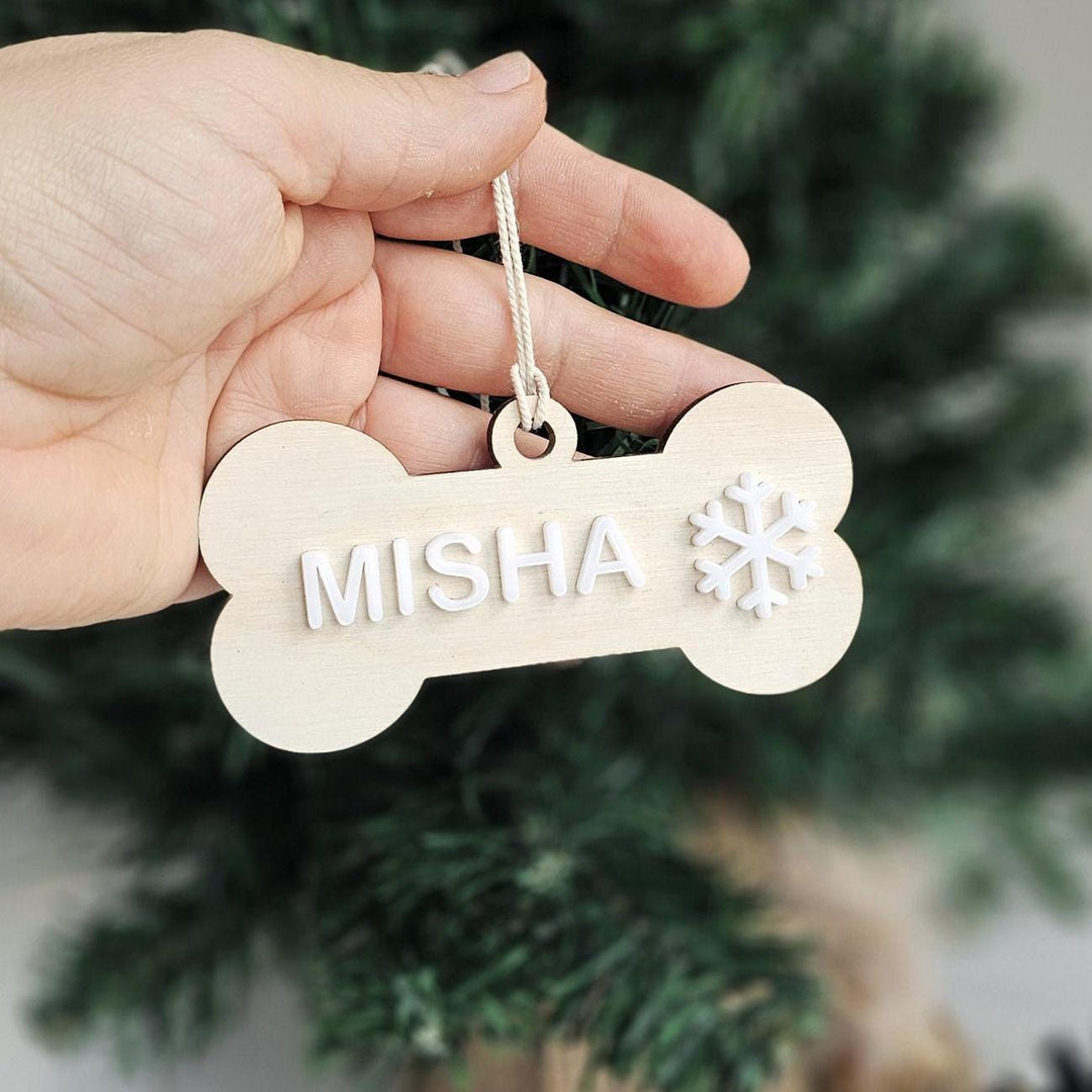Personalised wooden dog bone Christmas ornament with white acrylic name and a snowflake