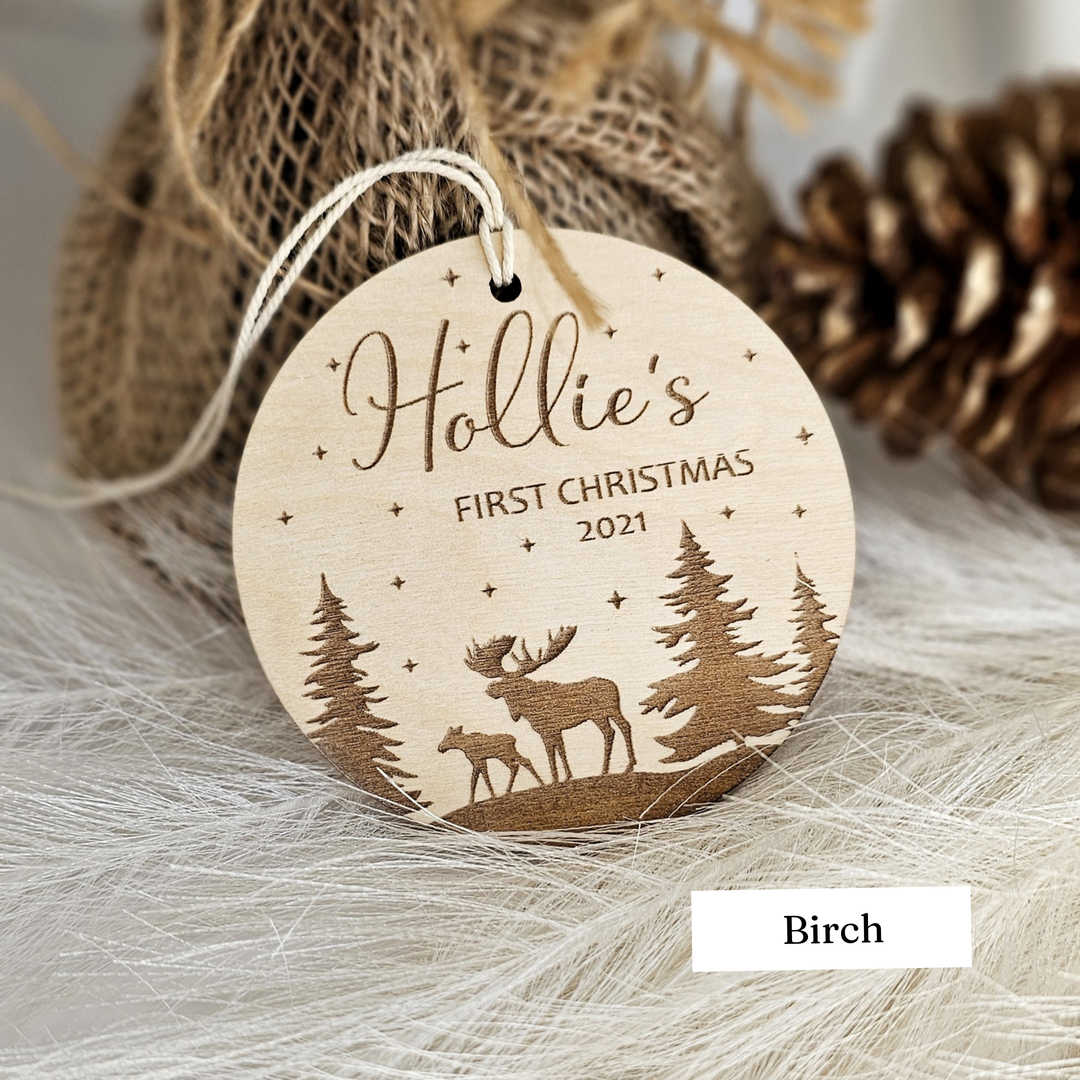 A wooden ornament with a deer silhouette and starry night sky design, labeled "Hollie's First Christmas 2021" and "Birches".